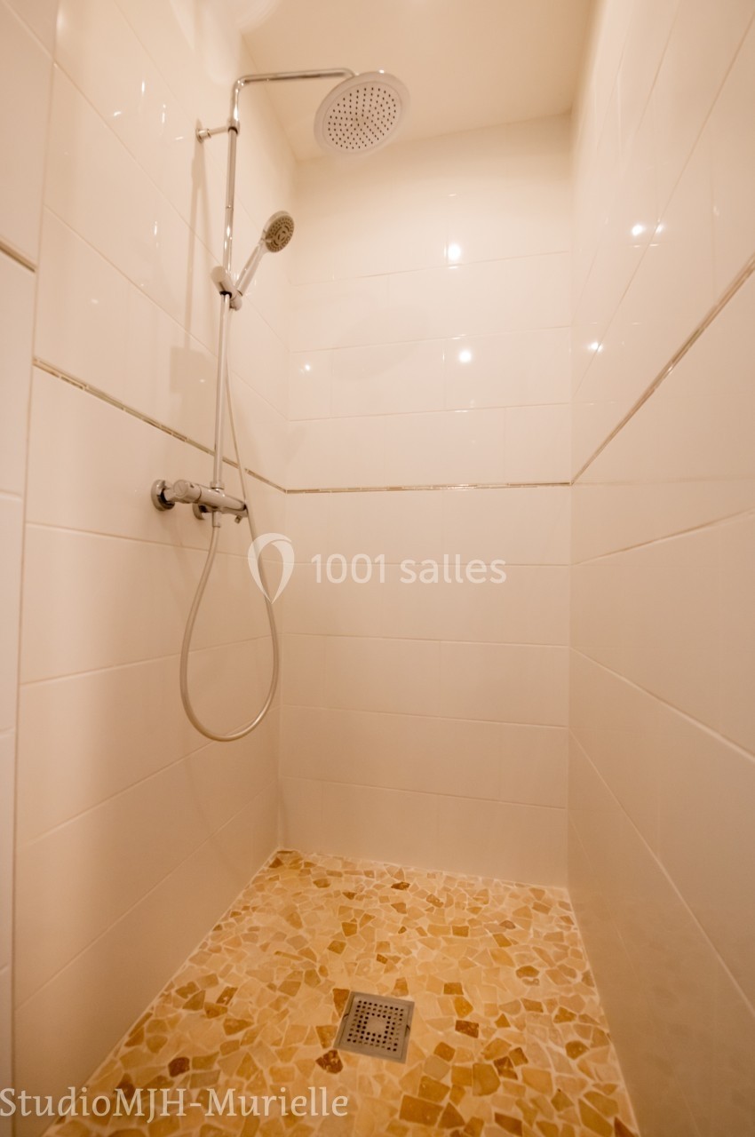Douche à l'italienne avec carrelage au sol en pierre naturelle et murs en faïence blanche.