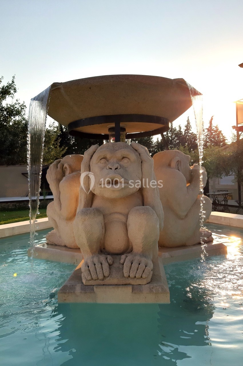 Fontaine ornée de sculptures de singes en pierre, avec de l'eau s'écoulant d'une vasque au sommet, au coucher du soleil.