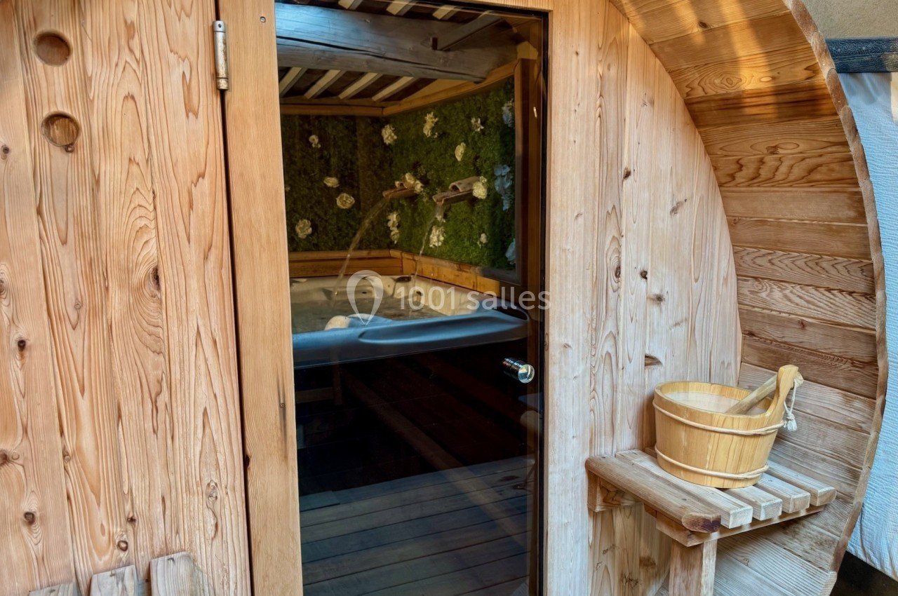 Cabine de sauna en bois avec porte vitrée, seau en bois et intérieur décoré de mousse végétale.