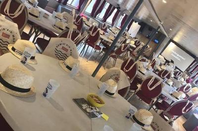 Salle de réception sur un bateau avec des tables dressées, des verres à champagne alignés et une vue sur l'eau en arrière…