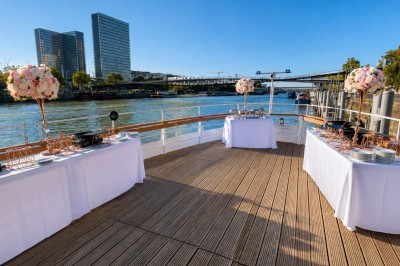 Miniature Location salle Paris 12 (Paris) - La Péniche Croisière de Bercy Corporate #2 Bateau rouge amarré le long d'une berge, entouré d'arbres aux couleurs automnales et sous un ciel dégagé.