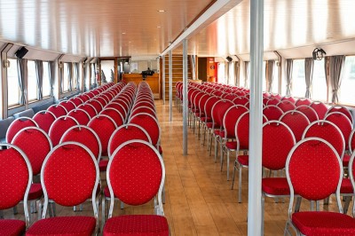 Miniature Location salle Paris 12 (Paris) - La Péniche Croisière de Bercy Corporate #4 Bateau rouge amarré le long d'une berge, entouré d'arbres aux couleurs automnales et sous un ciel dégagé.