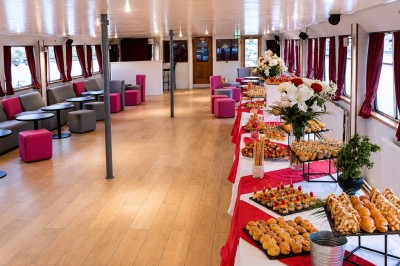 Miniature Location salle Paris 12 (Paris) - La Péniche Croisière de Bercy Corporate #6 Bateau rouge amarré le long d'une berge, entouré d'arbres aux couleurs automnales et sous un ciel dégagé.