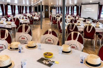 Miniature Location salle Paris 12 (Paris) - La Péniche Croisière de Bercy Corporate #5 Bateau rouge amarré le long d'une berge, entouré d'arbres aux couleurs automnales et sous un ciel dégagé.