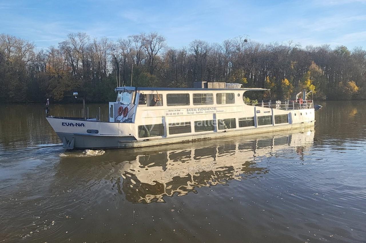 Bateau de tourisme blanc naviguant sur une rivière entourée d'arbres en automne sous un ciel dégagé.