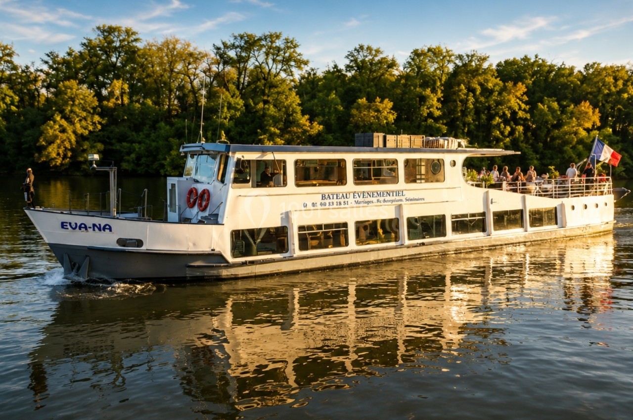 Bateau de croisière naviguant sur une rivière entourée d'arbres, avec des passagers à bord et un drapeau français.