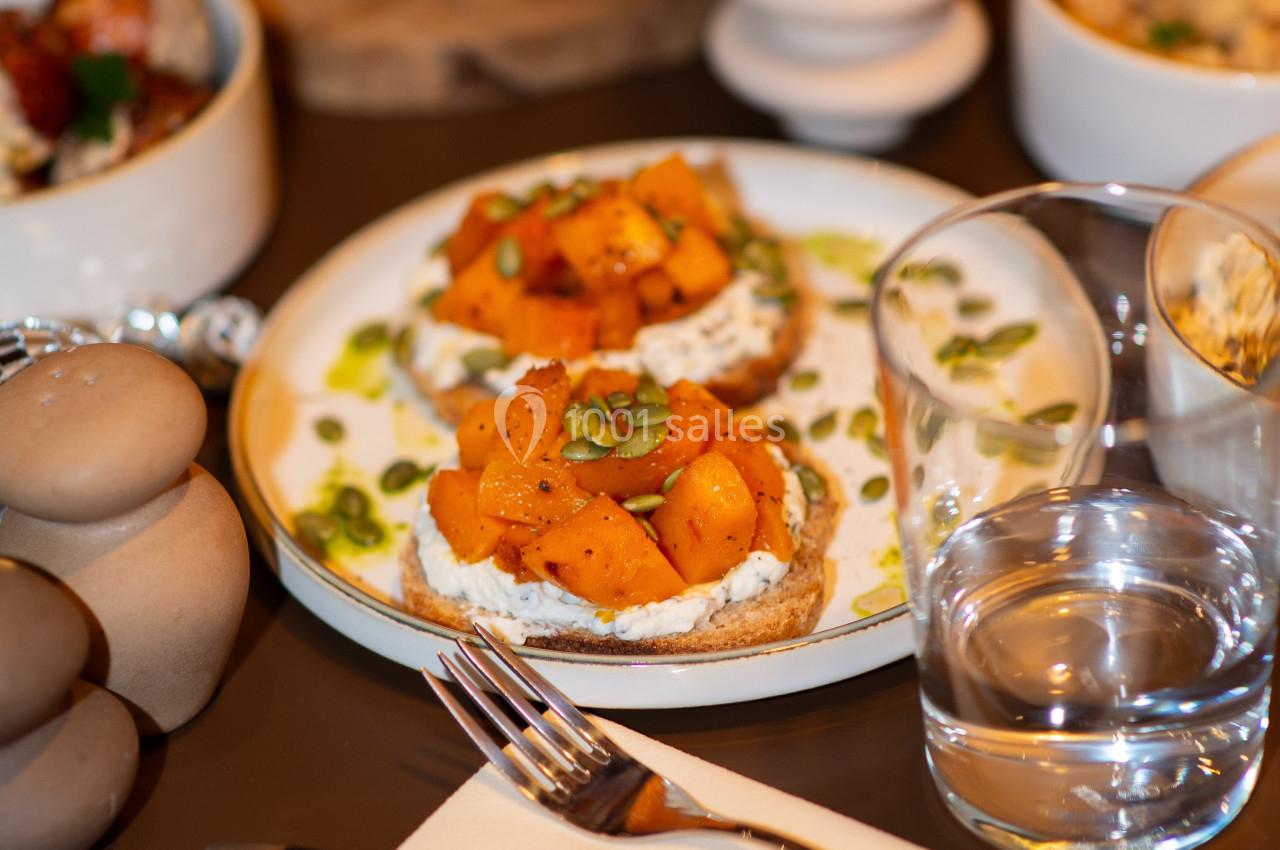 Tartines garnies de morceaux de courge rôtie, fromage frais et graines, servies sur une assiette blanche.