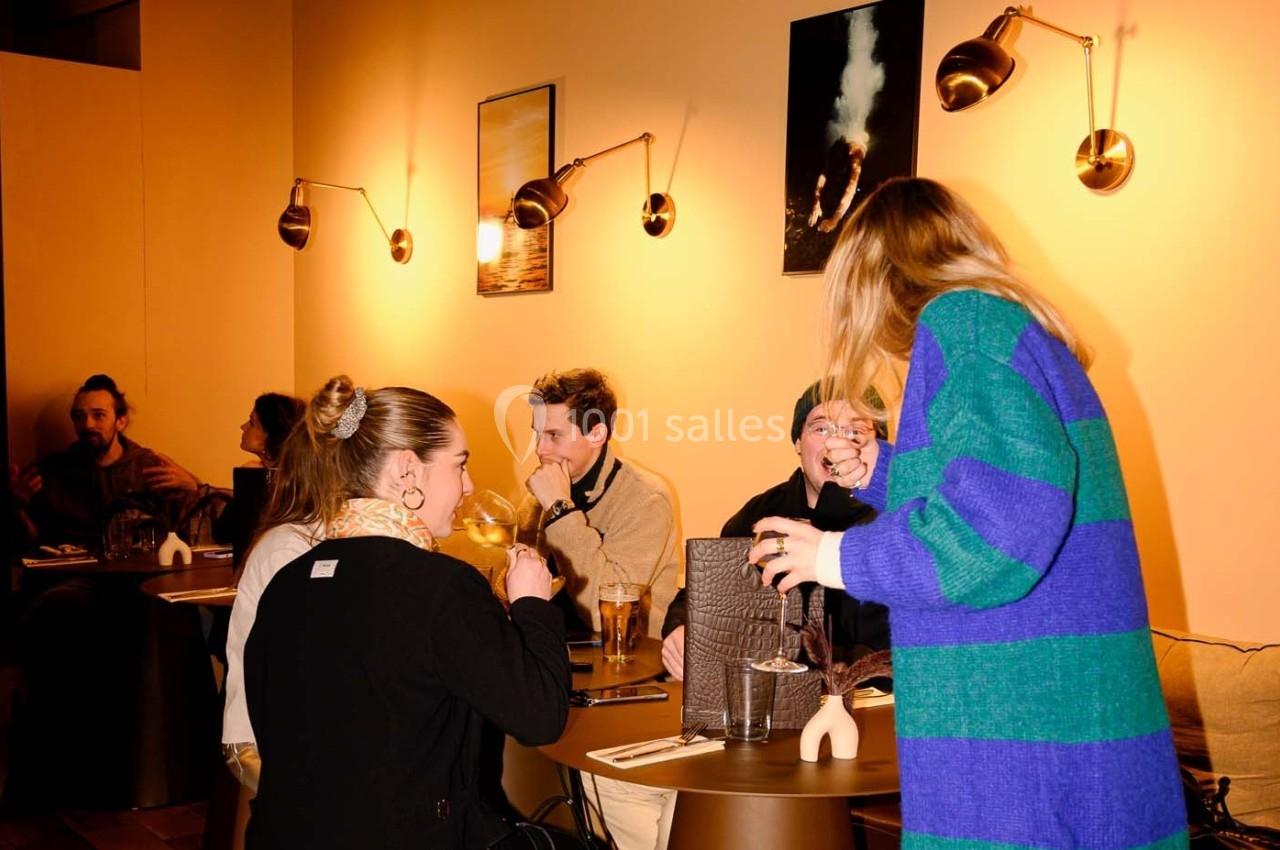 Des personnes discutent et partagent un repas dans un restaurant à l'éclairage chaleureux.