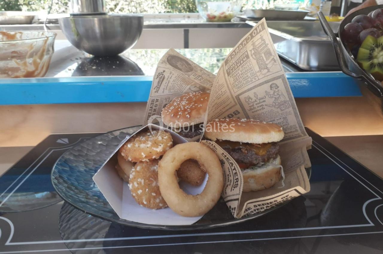 Assiette contenant deux burgers, des beignets et des nuggets, présentés dans des papiers imprimés façon journal.