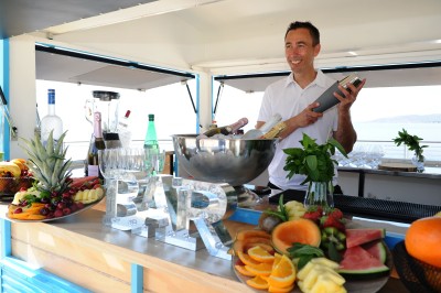 Miniature Traiteur Cannes (Alpes-Maritimes) - Azur Traiteur Events #32 Un food truck bleu avec trois personnes souriantes en tablier devant un comptoir en bois.