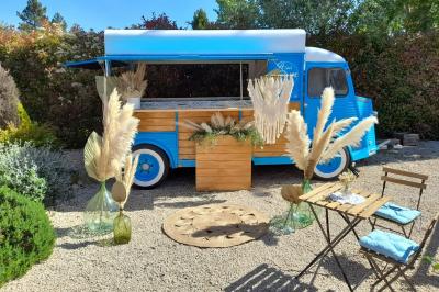 Miniature Traiteur Cannes (Alpes-Maritimes) - Azur Traiteur Events #23 Camion-restaurant bleu vintage devant une concession Mercedes-Benz, avec tables et chaises disposées en terrasse.