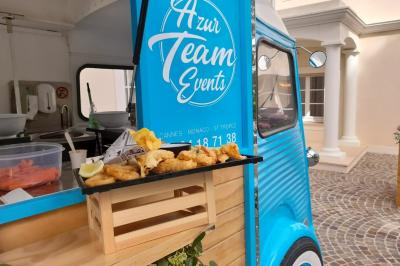 Miniature Traiteur Cannes (Alpes-Maritimes) - Azur Traiteur Events #8 Camion-restaurant bleu vintage devant une concession Mercedes-Benz, avec tables et chaises disposées en terrasse.