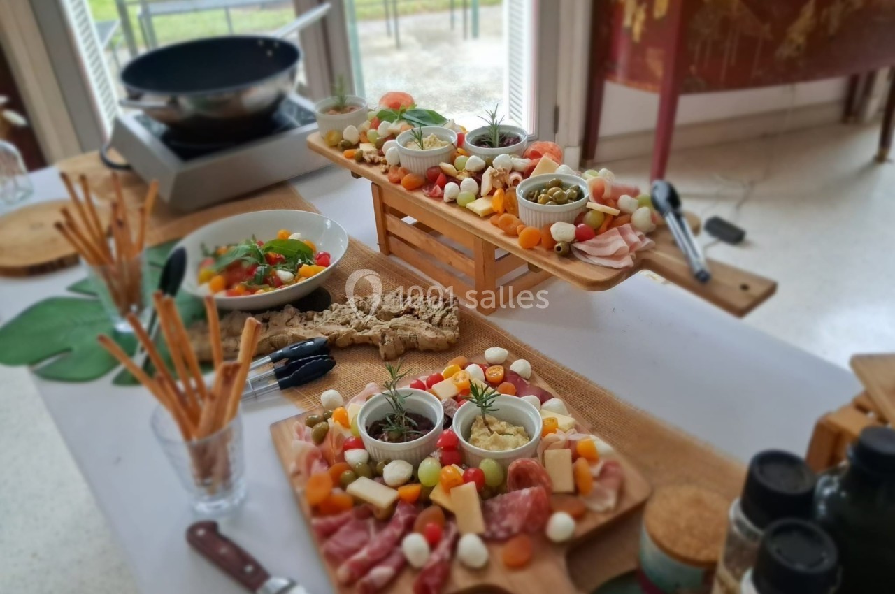 Plateaux de charcuterie, fromages et légumes colorés disposés sur une table avec des ustensiles et des condiments.