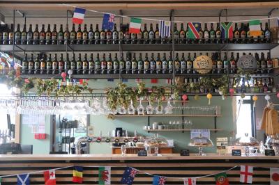 Miniature Location salle Villeneuve-d'Ascq (Nord) - Brasserie Moulins D'ascq #9 Bar décoré avec des drapeaux internationaux, des bouteilles alignées sur des étagères et des verres suspendus au plafond.