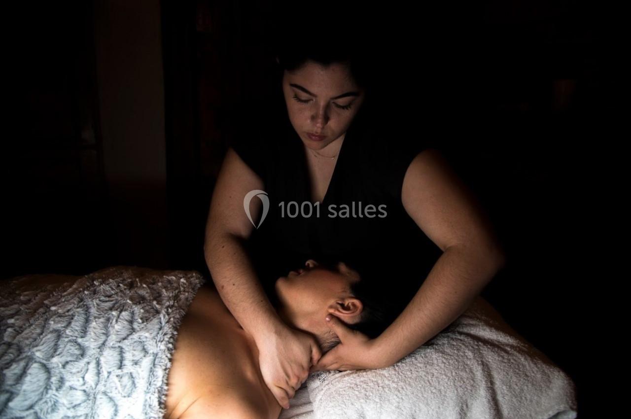 Femme effectuant un massage du cou sur une personne allongée, enveloppée dans une serviette blanche.