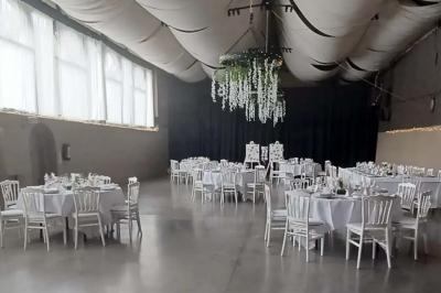 Miniature Location salle Héron (Liège) - Chateau Ferme de Marsinne #4 Salle de réception décorée avec des tables rondes dressées, nappes blanches et guirlandes suspendues au plafond.