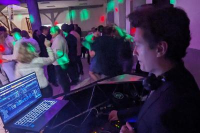 Un homme s'exprime au micro devant un public rassemblé dans une cour extérieure entourée de végétation.