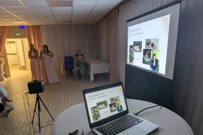 Un homme s'exprime au micro devant un public rassemblé dans une cour extérieure entourée de végétation.