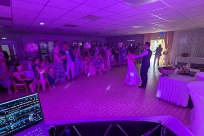 Un homme s'exprime au micro devant un public rassemblé dans une cour extérieure entourée de végétation.