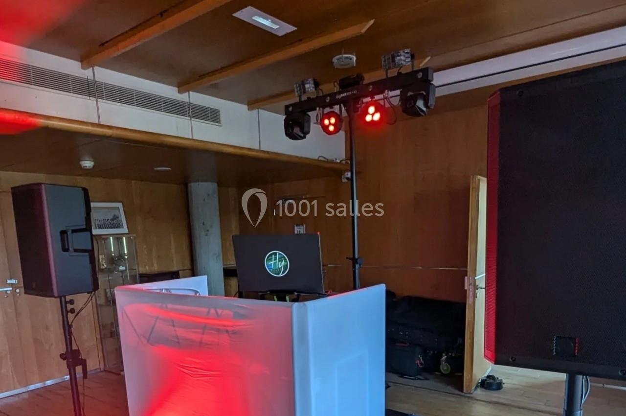 Installation de matériel de sonorisation et d'éclairage dans une salle en bois, avec une table de DJ et des projecteurs…