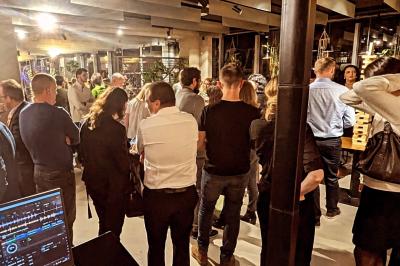 Un homme s'exprime au micro devant un public rassemblé dans une cour extérieure entourée de végétation.