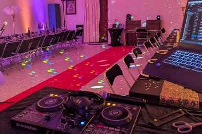 Un homme s'exprime au micro devant un public rassemblé dans une cour extérieure entourée de végétation.