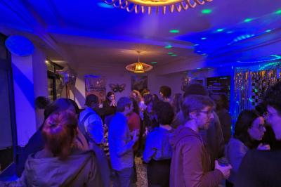 Un homme s'exprime au micro devant un public rassemblé dans une cour extérieure entourée de végétation.