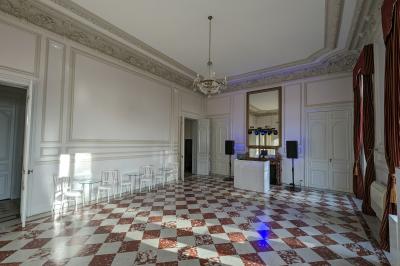 Un homme s'exprime au micro devant un public rassemblé dans une cour extérieure entourée de végétation.