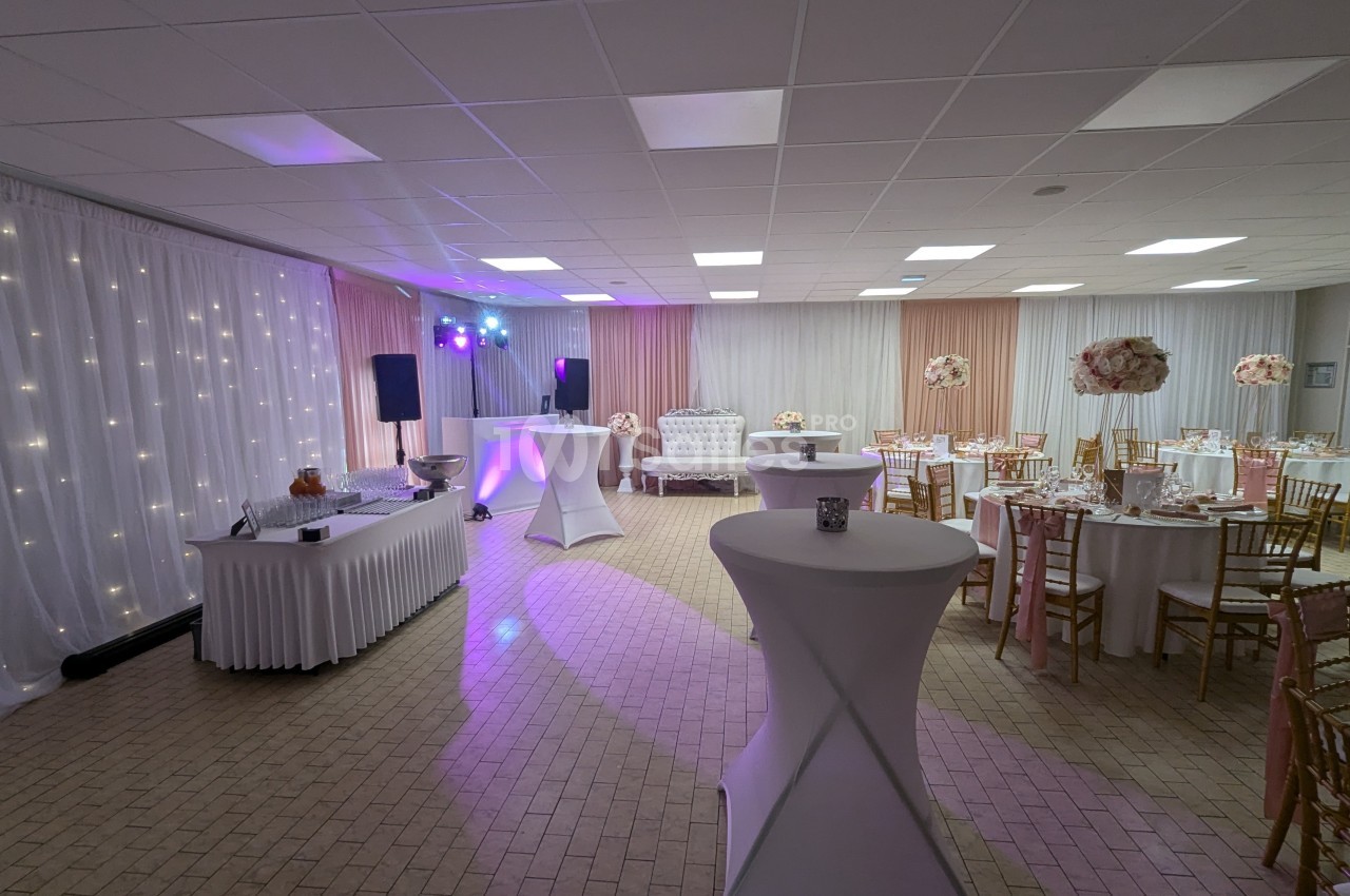 Salle de réception décorée avec des tables rondes, des chaises dorées, un buffet et un éclairage tamisé.