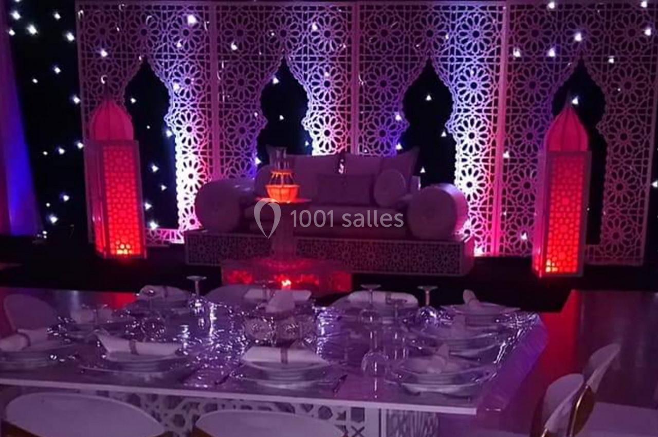 Décoration de salle avec table dressée, canapé orné et panneaux ajourés illuminés dans une ambiance tamisée.