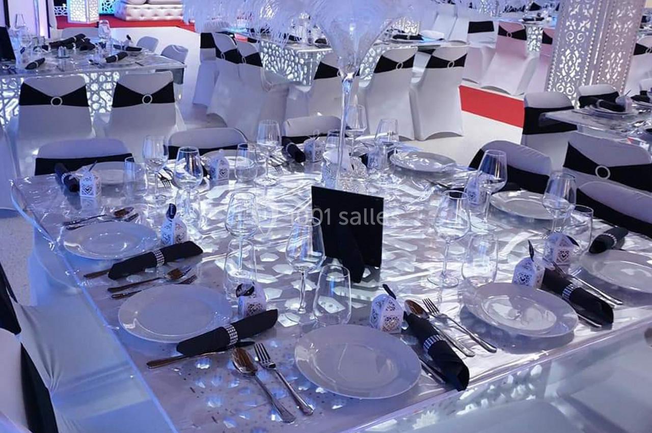 Table dressée avec vaisselle élégante, serviettes noires, verres et décoration raffinée dans une salle de réception.