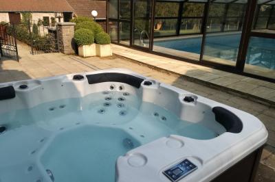Chambre avec lit double, baignoire îlot, parquet, carrelage hexagonal et échelle porte-serviettes.