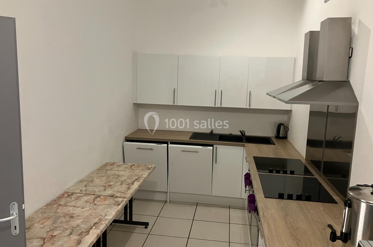 Cuisine moderne avec plan de travail en bois, plaques de cuisson, hotte en inox, et table en marbre.