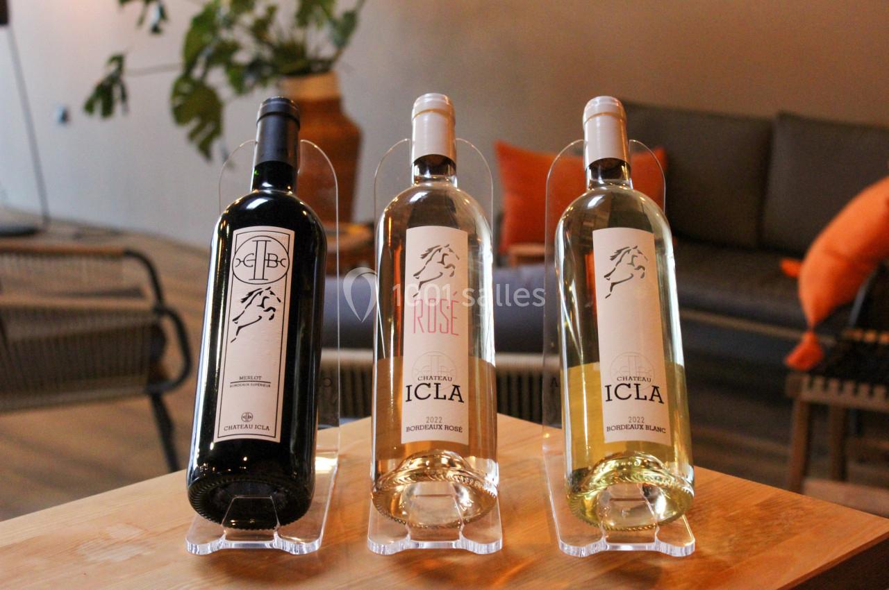 Trois bouteilles de vin Château Icla (rouge, rosé et blanc) posées sur une table en bois dans un intérieur chaleureux.