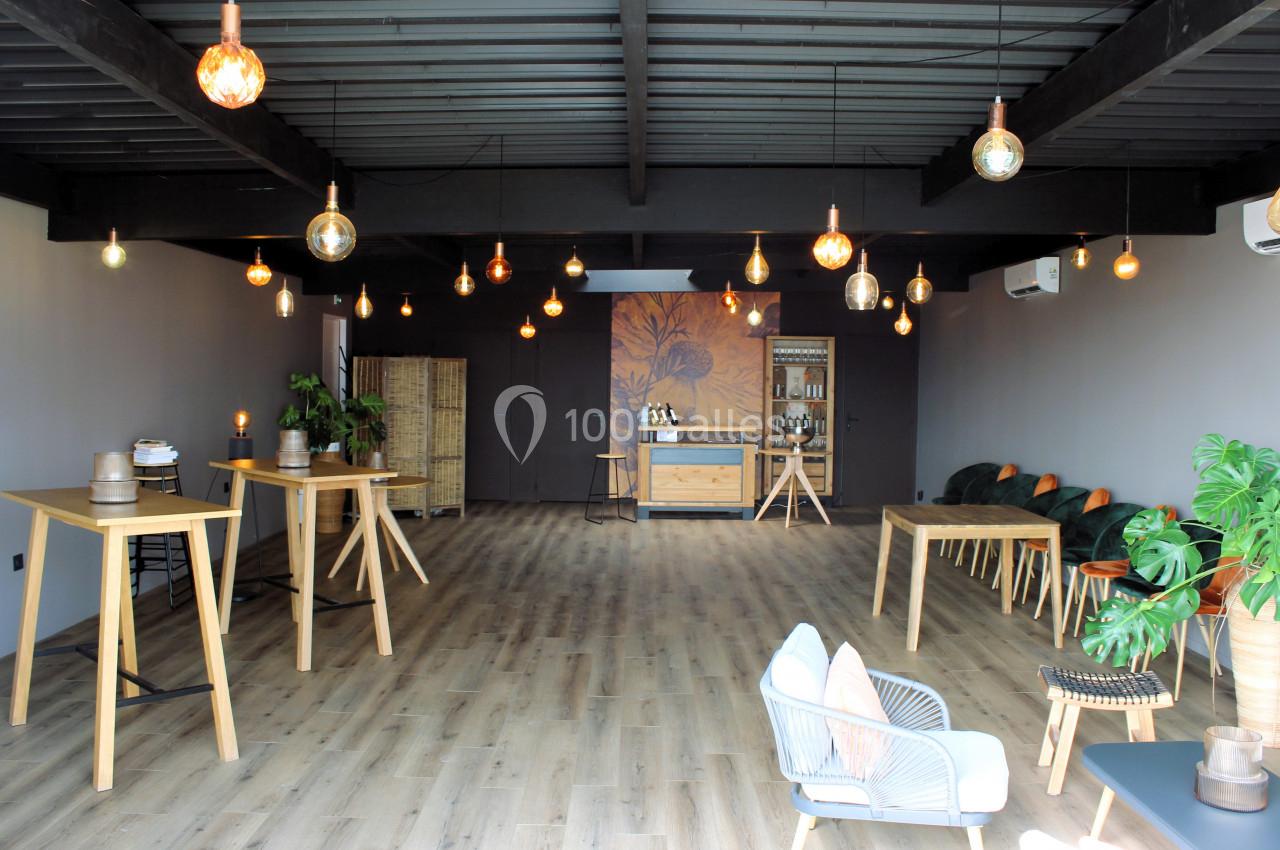 Salle lumineuse avec parquet en bois, mobilier moderne en bois clair, plantes vertes et éclairage suspendu chaleureux.