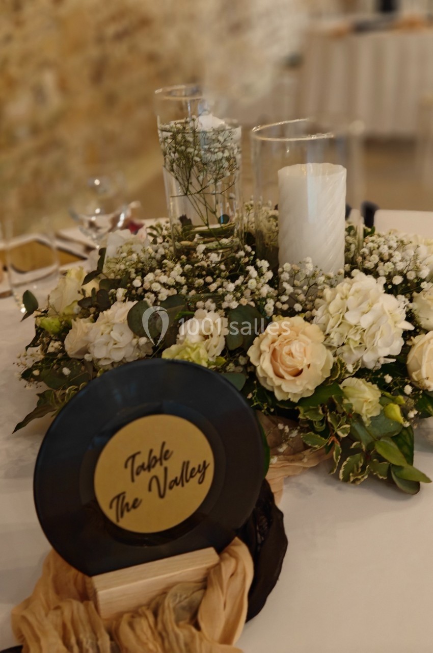 Centre de table avec fleurs blanches, bougie cylindrique et disque vinyle portant l'inscription ’Table The Valley’.