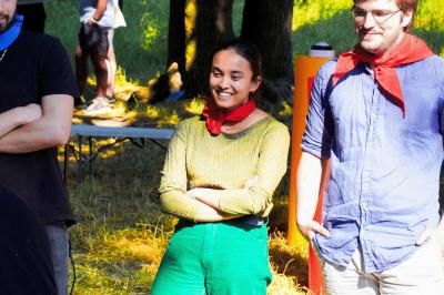 Une personne en combinaison rouge se tient devant un groupe d'adultes et d'enfants sur une aire extérieure.