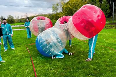 Une personne en combinaison rouge se tient devant un groupe d'adultes et d'enfants sur une aire extérieure.