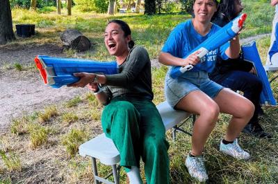 Une personne en combinaison rouge se tient devant un groupe d'adultes et d'enfants sur une aire extérieure.