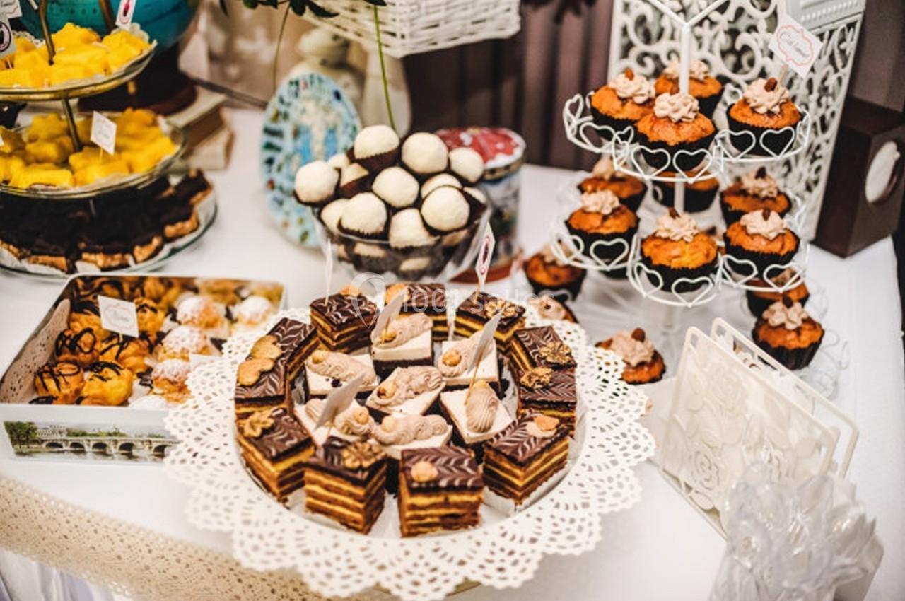 Table garnie de pâtisseries variées, dont gâteaux en couches, truffes au chocolat et cupcakes décorés.