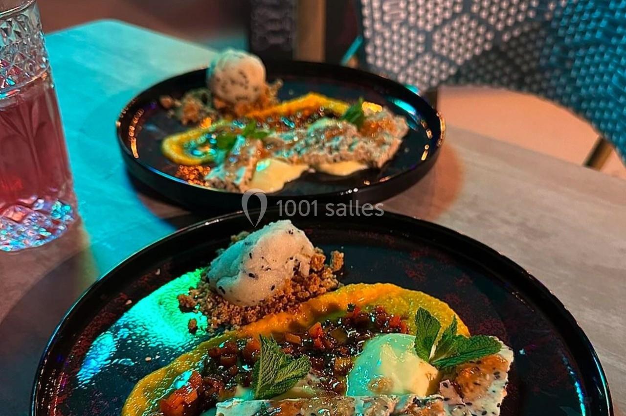 Assiette de dessert composée de crème glacée, purée orange, garnitures croquantes et feuilles de menthe.