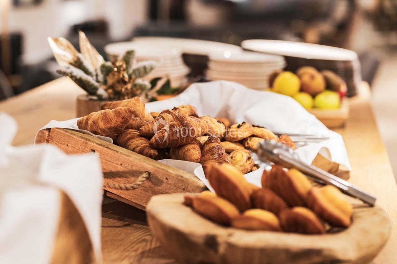 Plateau de croissants et viennoiseries disposé sur une table en bois, entouré de fruits et de décorations.