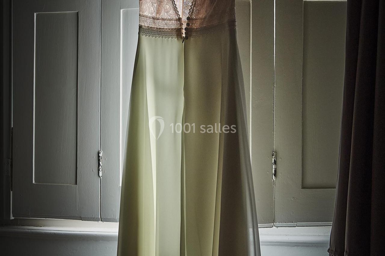 Robe élégante suspendue à un cintre devant une fenêtre, éclairée par une lumière douce.