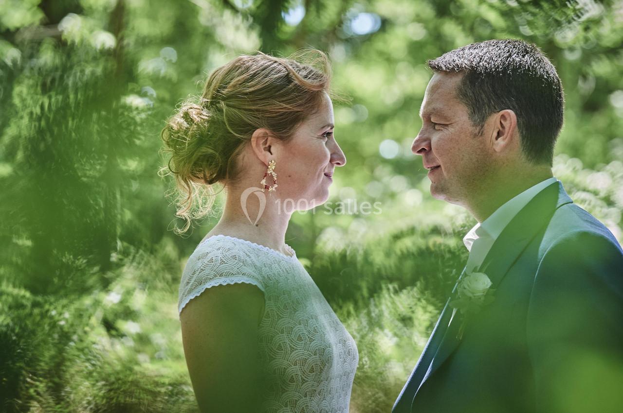 Un couple se regarde dans un jardin verdoyant, éclairé par une lumière naturelle.