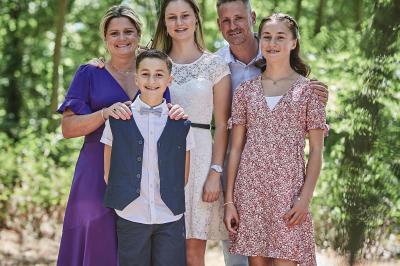 Un grand groupe de personnes souriantes levant les bras, rassemblées dans un parc pour une célébration.
