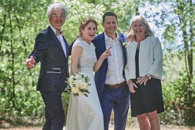 Un grand groupe de personnes souriantes levant les bras, rassemblées dans un parc pour une célébration.