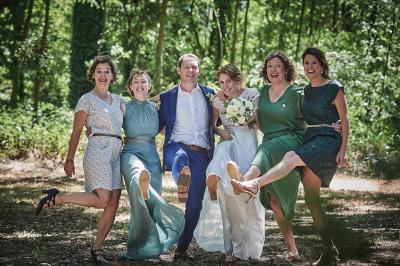 Un grand groupe de personnes souriantes levant les bras, rassemblées dans un parc pour une célébration.