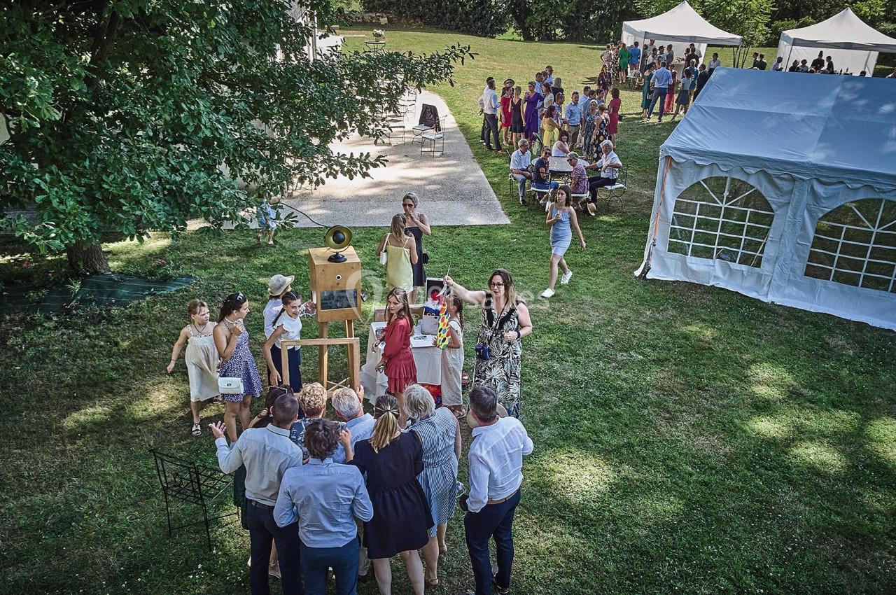 Groupe de personnes réunies dans un jardin autour d'une animation avec des tentes blanches en arrière-plan.