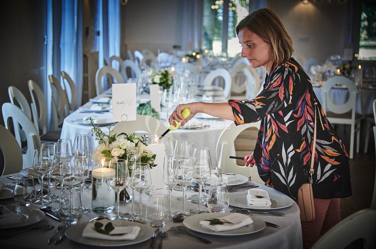 Une femme allume une bougie sur une table élégamment dressée dans une salle de réception.