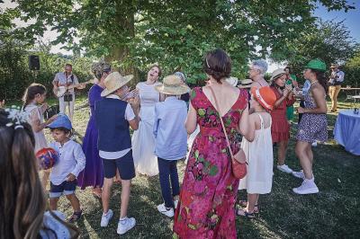 Un grand groupe de personnes souriantes levant les bras, rassemblées dans un parc pour une célébration.